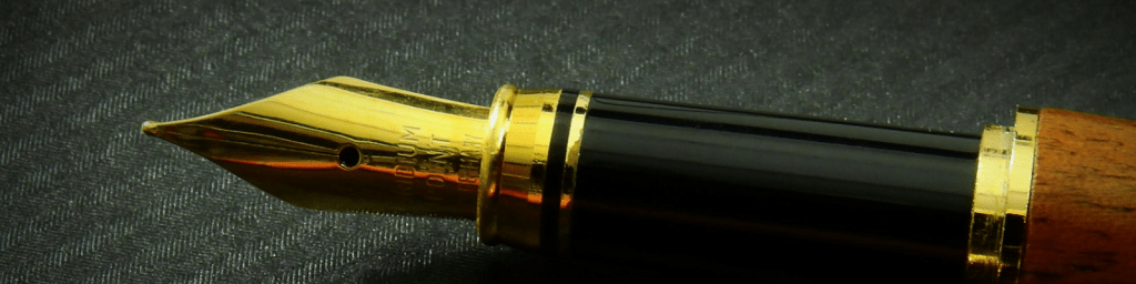 A golden pen lying on black paper.