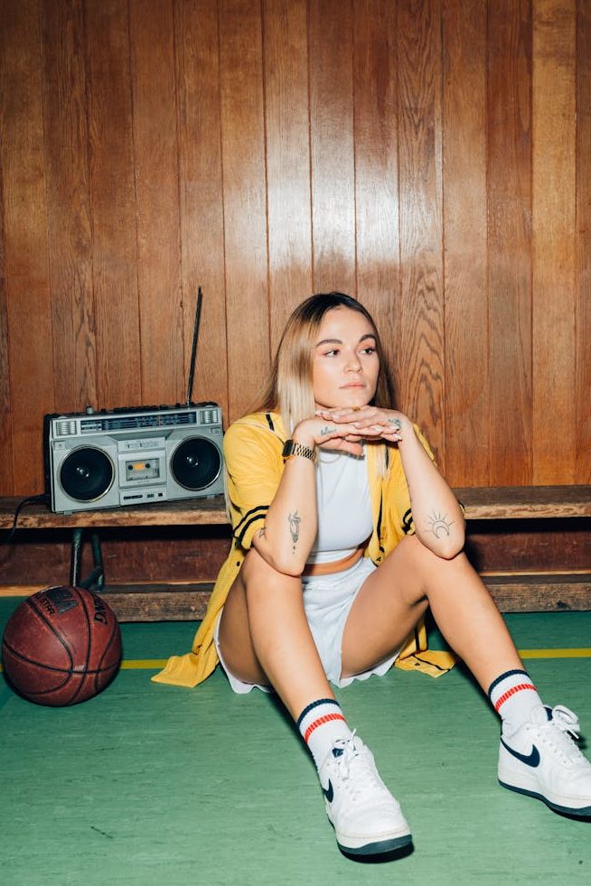 A woman in 1980s fashion in a room with wooden panelling.