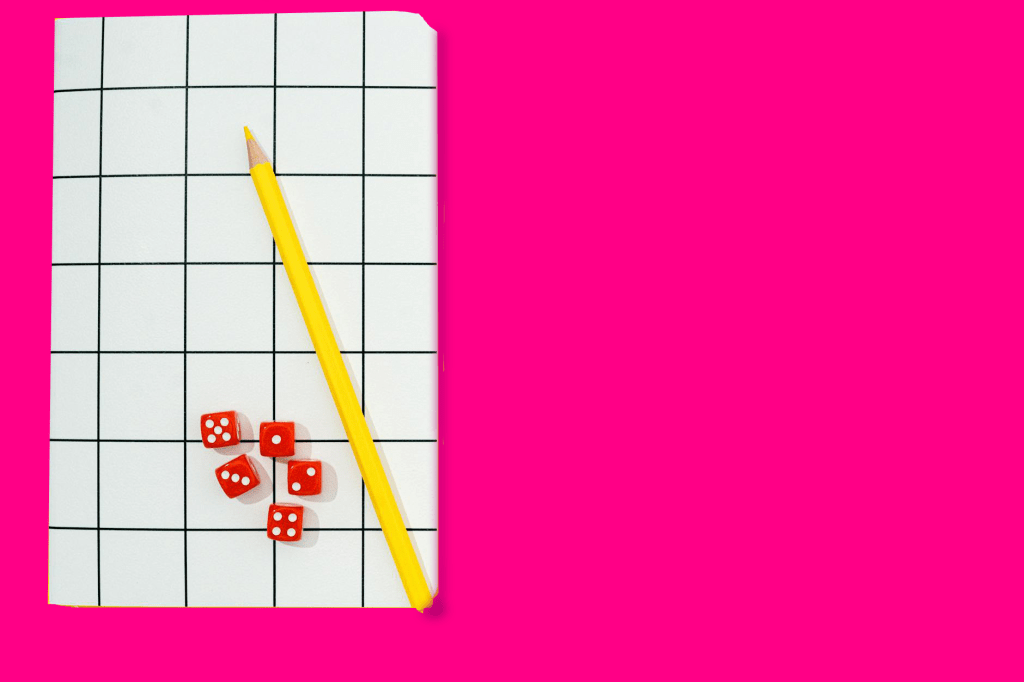 A yellow pencil, grid paper, and dice on a pink background.
