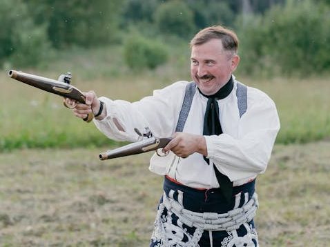A historical re-enactor with two flintlock pistols.