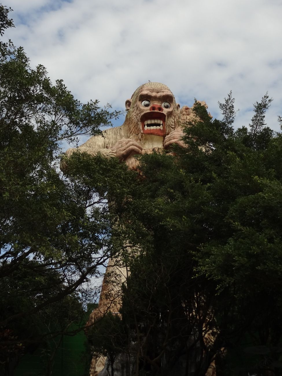 A statue of bigfoot above some trees.