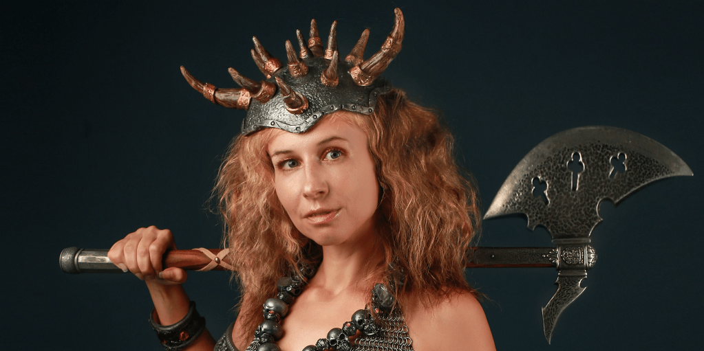 A woman in chainmail armour and a horned helmet holding an axe.